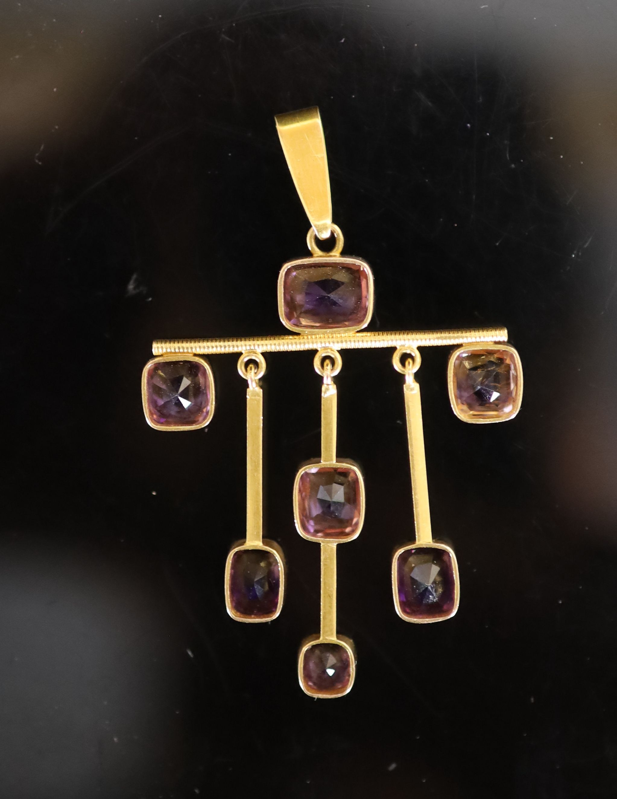 A stylish early 20th century gold and seven stone amethyst set drop pendant